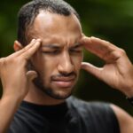 Man holding his temples due to a severe headache, illustrating common concussion symptoms and the need for medical evaluation and continued care.